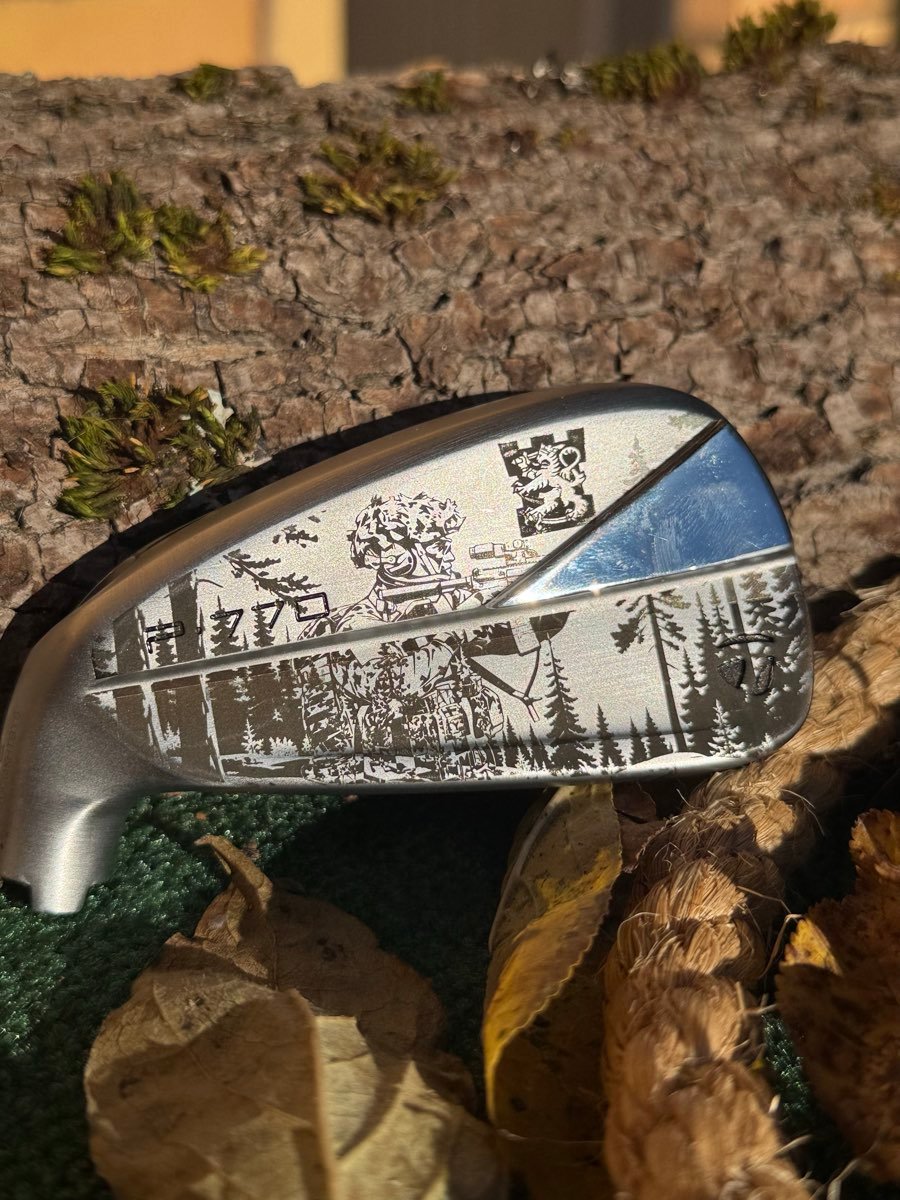 Yksityiskohtainen metsämaisema ja leijonavaakuna kaiverrettuna TaylorMade-rautaan